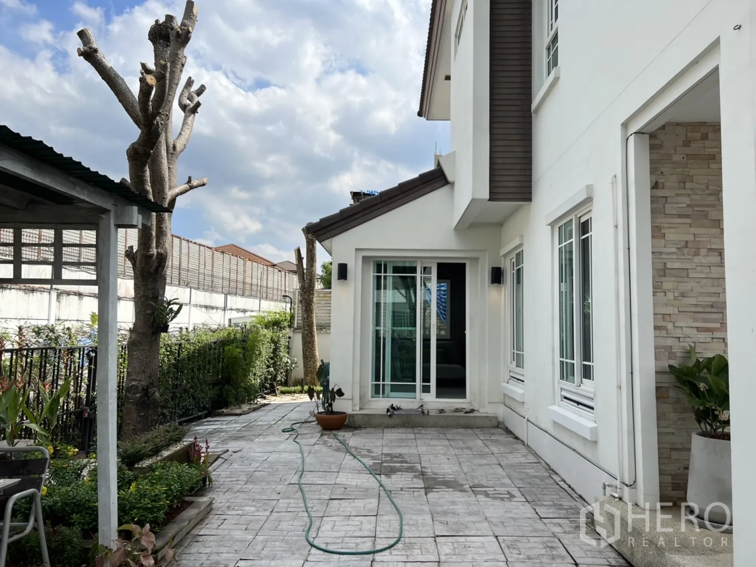 Detached House for rent in Bang Kapi, Bangkok - Side yard with landscaped greenery and a wide tiled patio alongside the house.