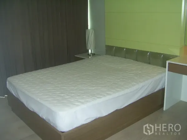Condominium for rent in Khlong Toei, Bangkok - Second bedroom featuring a green accent wall, large bed, and bedside lamp.