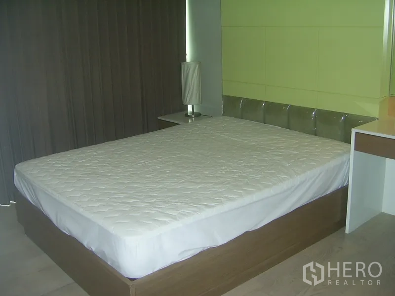 Condominium for rent in Khlong Toei, Bangkok - Second bedroom featuring a green accent wall, large bed, and bedside lamp.