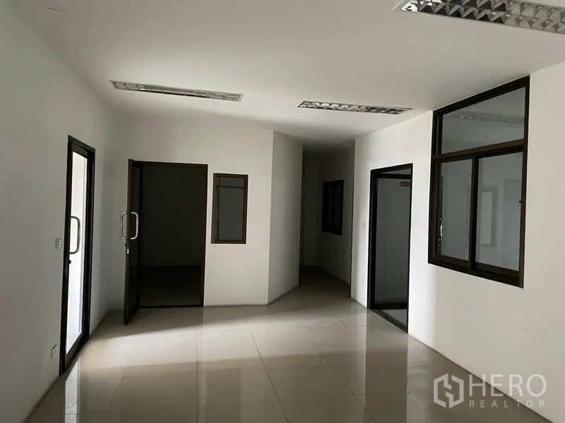 Warehouse for rent in Prawet, Bangkok - Clean internal office rooms with tiled flooring, glass windows, and fluorescent lighting.