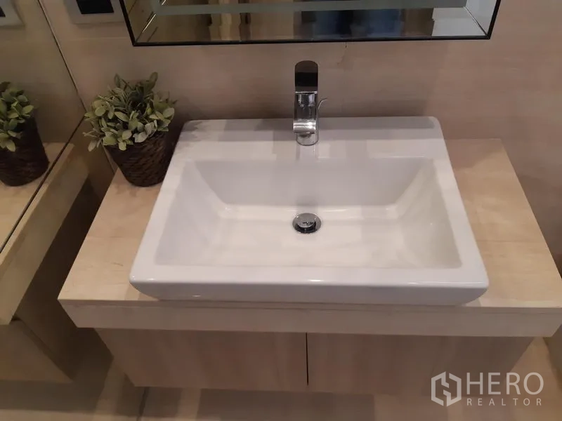 Condominium for rent in Watthana, Bangkok - Square vanity sink on a light wood cabinet with wall mirror.