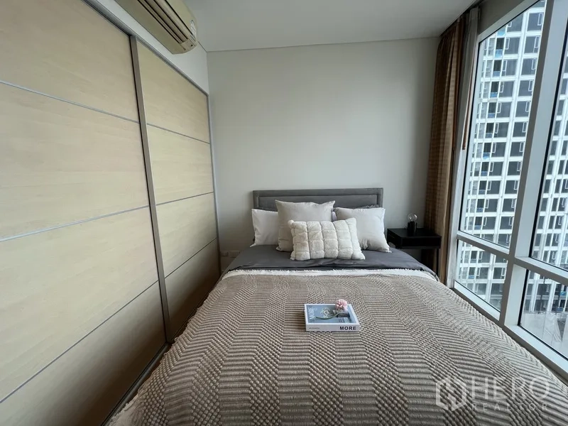 Condominium for rent in Watthana, Bangkok - Second bedroom with built-in wardrobes and bed by large windows.
