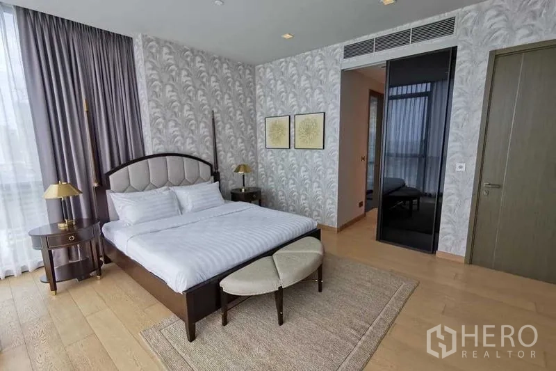 Condominium for rent or sale in Watthana, Bangkok - Master bedroom with padded headboard, bench and patterned wallpaper.