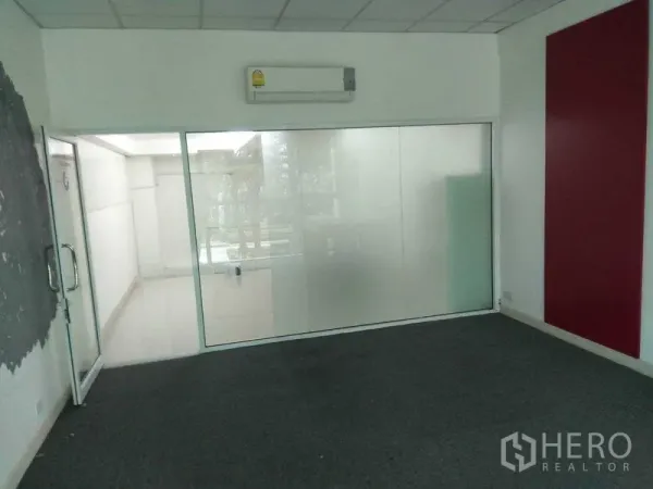 Retail Space for rent in Huai Khwang, Bangkok - Carpeted room with a frosted glass partition, wall-mounted air conditioner and glass door.