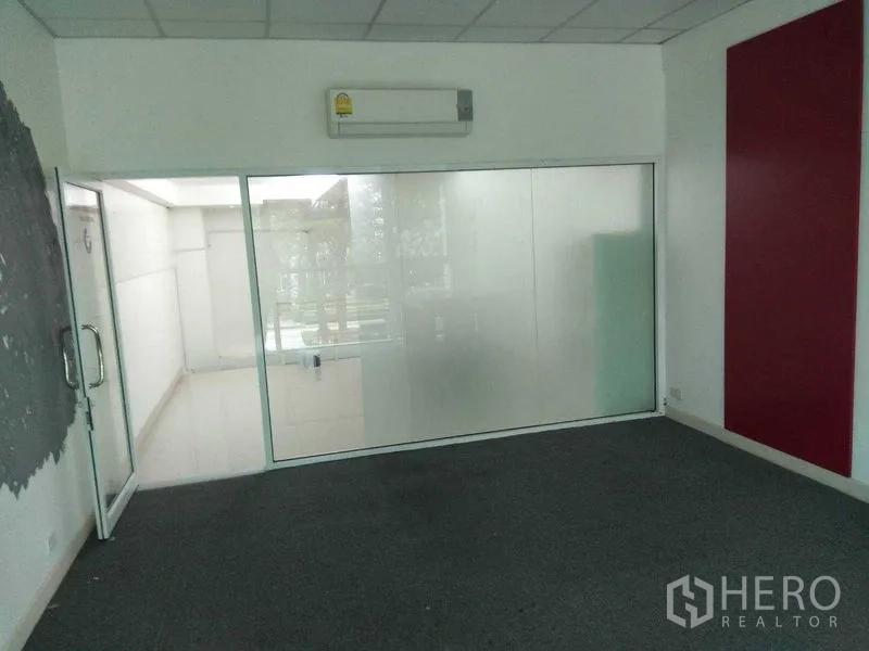 Retail Space for rent in Huai Khwang, Bangkok - Carpeted room with a frosted glass partition, wall-mounted air conditioner and glass door.