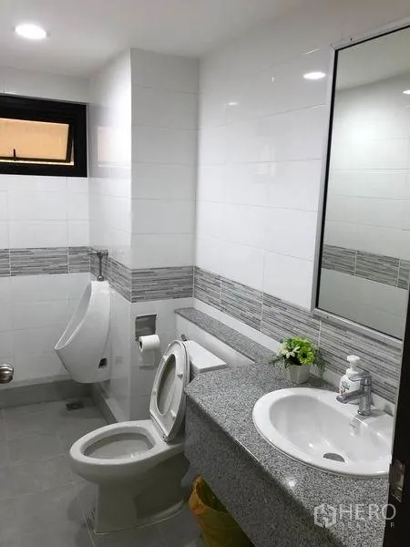 Home Office for rent in Khlong Toei, Bangkok - Modern tiled bathroom with toilet, urinal, vanity and mirror.