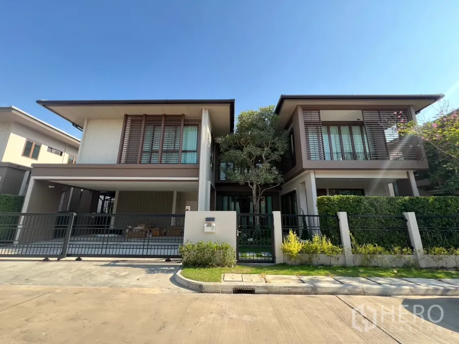 独立式住宅 出租或出售在Bang Kapi, Bangkok - 现代两层独栋别墅，带电动门庭院与景观绿篱，蓝天下外观。