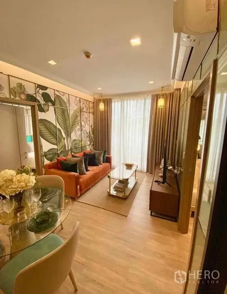 公寓 出租在Watthana, Bangkok - 采光充足的客厅，橙色沙发、电视柜与通往阳台的纱帘。