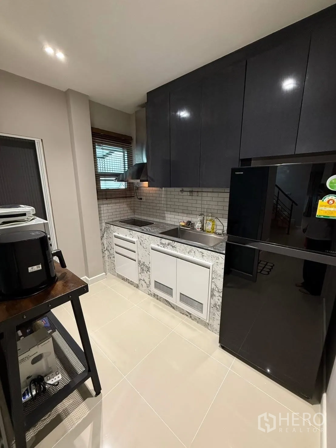 独栋房屋 for rent in Prawet, Bangkok - 厨房另一角，黑色冰箱、地铁砖挡墙与内置柜体