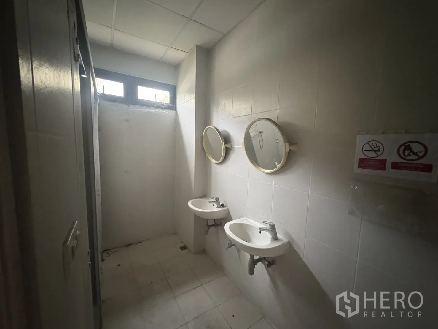 Factory for rent or sale in Samut Prakan - Restroom with urinal partitions and sinks in a tiled room.