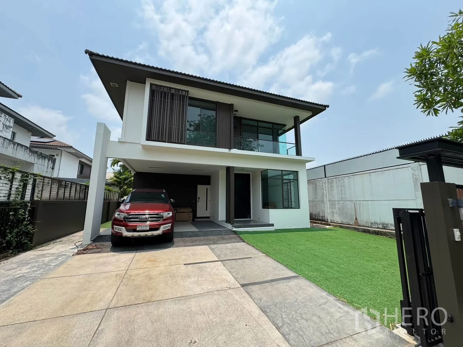Detached House for rent in Prawet, Bangkok - Front elevation of the detached house with driveway and green lawn.