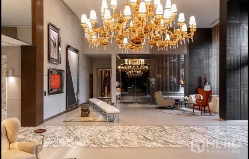 Condominium for rent or sale in Watthana, Bangkok - Grand lobby with marble floors, gold chandelier and lounge seating.