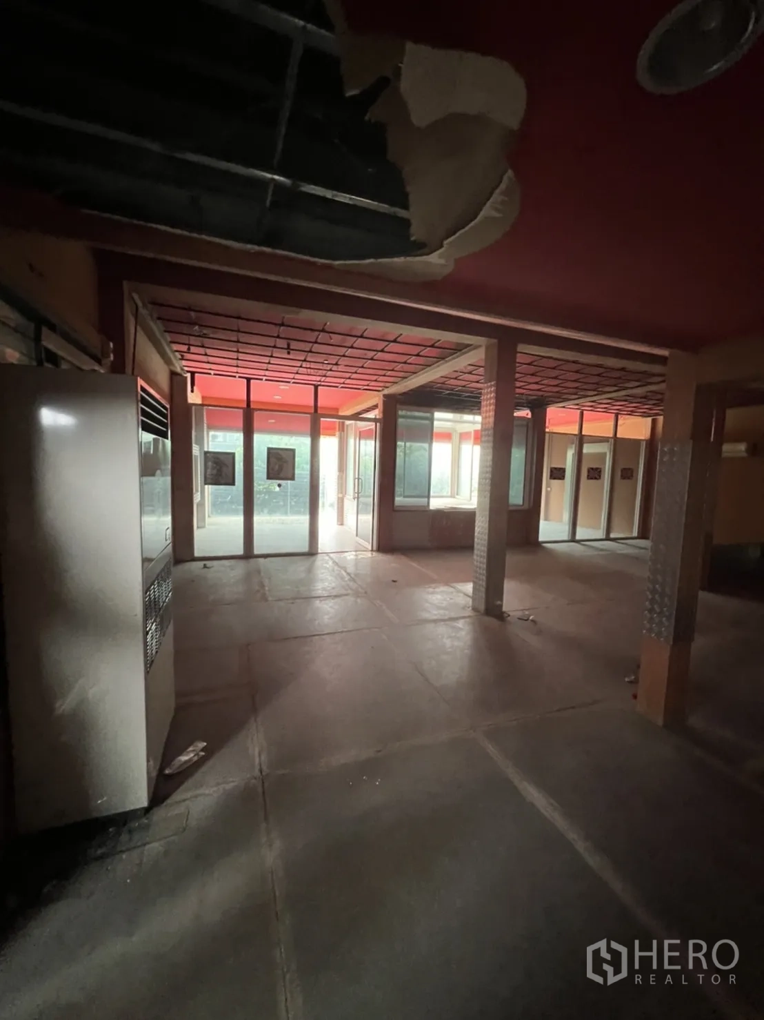 Shophouse for rent in Watthana, Bangkok - Large upper floor with exposed ceiling sections and glass walls, suitable for renovation.