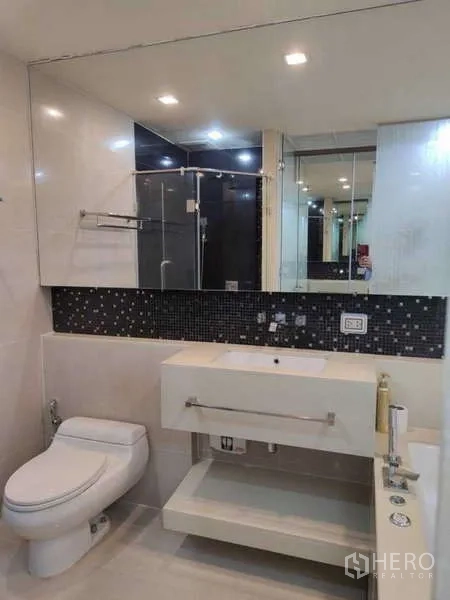 Condominium for rent in Bang Rak, Bangkok - Clean bathroom with vanity, toilet and glass-enclosed shower.