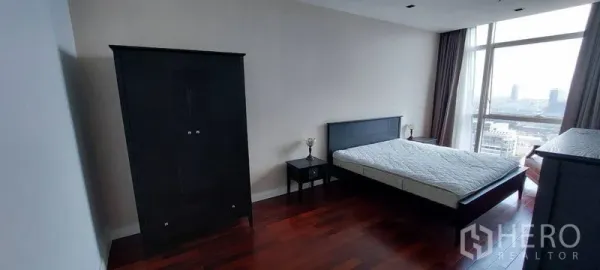 公寓 出租在Pathum Wan, Bangkok - 曼谷帕吞旺公寓的宽敞卧室，深色木地板，大窗户城市景观，黑色床与衣柜。