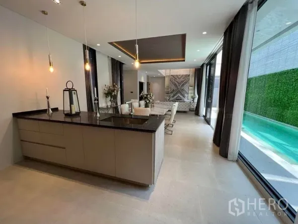 独立式住宅 出售在Suan Luang, Bangkok - 开放式客餐厅与岛台厨房，落地玻璃俯瞰私家泳池的现代空间
