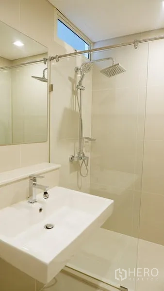 Condominium for rent in Watthana, Bangkok - Bathroom with square sink, large mirror and a glass-enclosed rain shower.