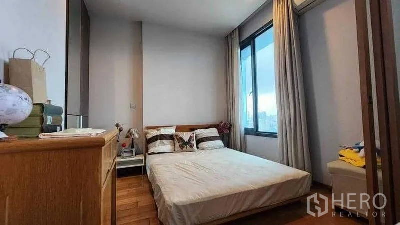 Condominium for rent in Khlong Toei, Bangkok - Cozy bedroom with window and curtains looking over Bangkok.