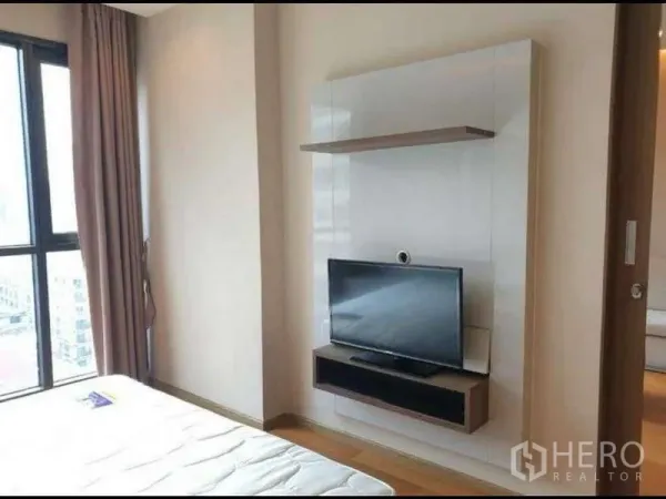 公寓 出租在Bang Rak, Bangkok - 卧室一角设墙挂式电视柜，配高窗与窗帘，现代简约风格。