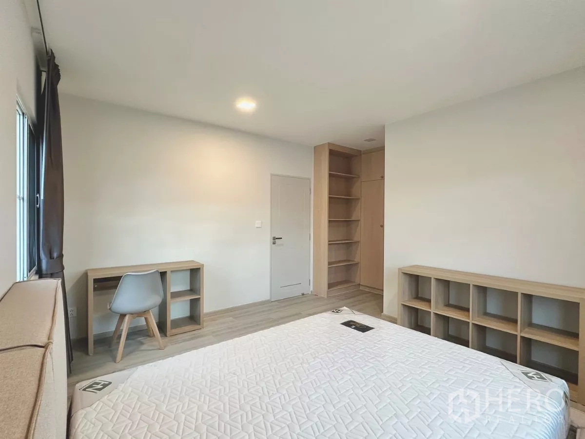 Detached House for rent in Bang Phli, Samut Prakan - Second bedroom with double bed, study desk and open shelving.