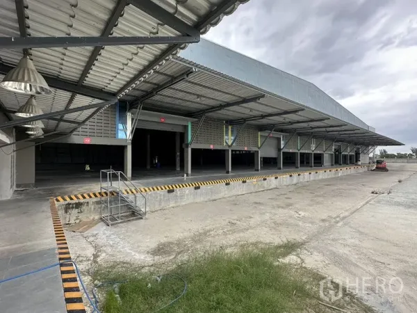 Factory for rent in Bang Sao Thong, Samut Prakan - Row of covered loading docks with elevated truck platforms and safety markings.