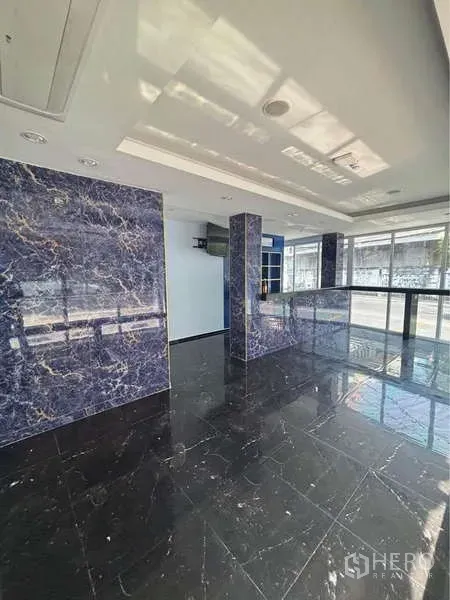 Retail Space for rent in Khlong Toei, Bangkok - Open retail floor with glossy black marble tiles, blue-veined columns and floor-to-ceiling windows.