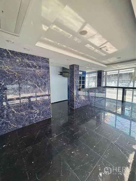 Retail Space for rent in Khlong Toei, Bangkok - Open retail floor with glossy black marble tiles, blue-veined columns and floor-to-ceiling windows.