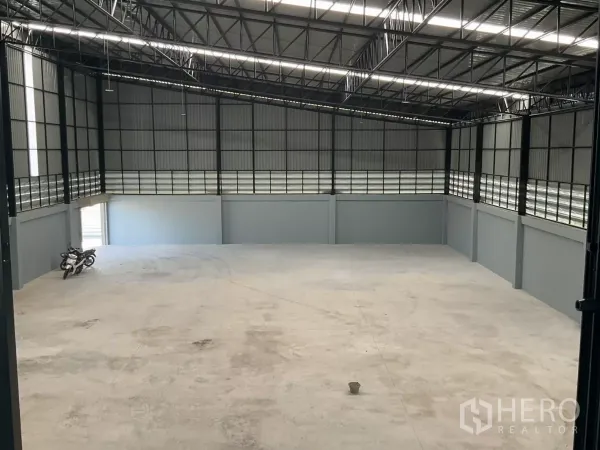 Factory for sale in Samut Sakhon - Wide view of open production space with ventilated wall panels and bright roof lighting.