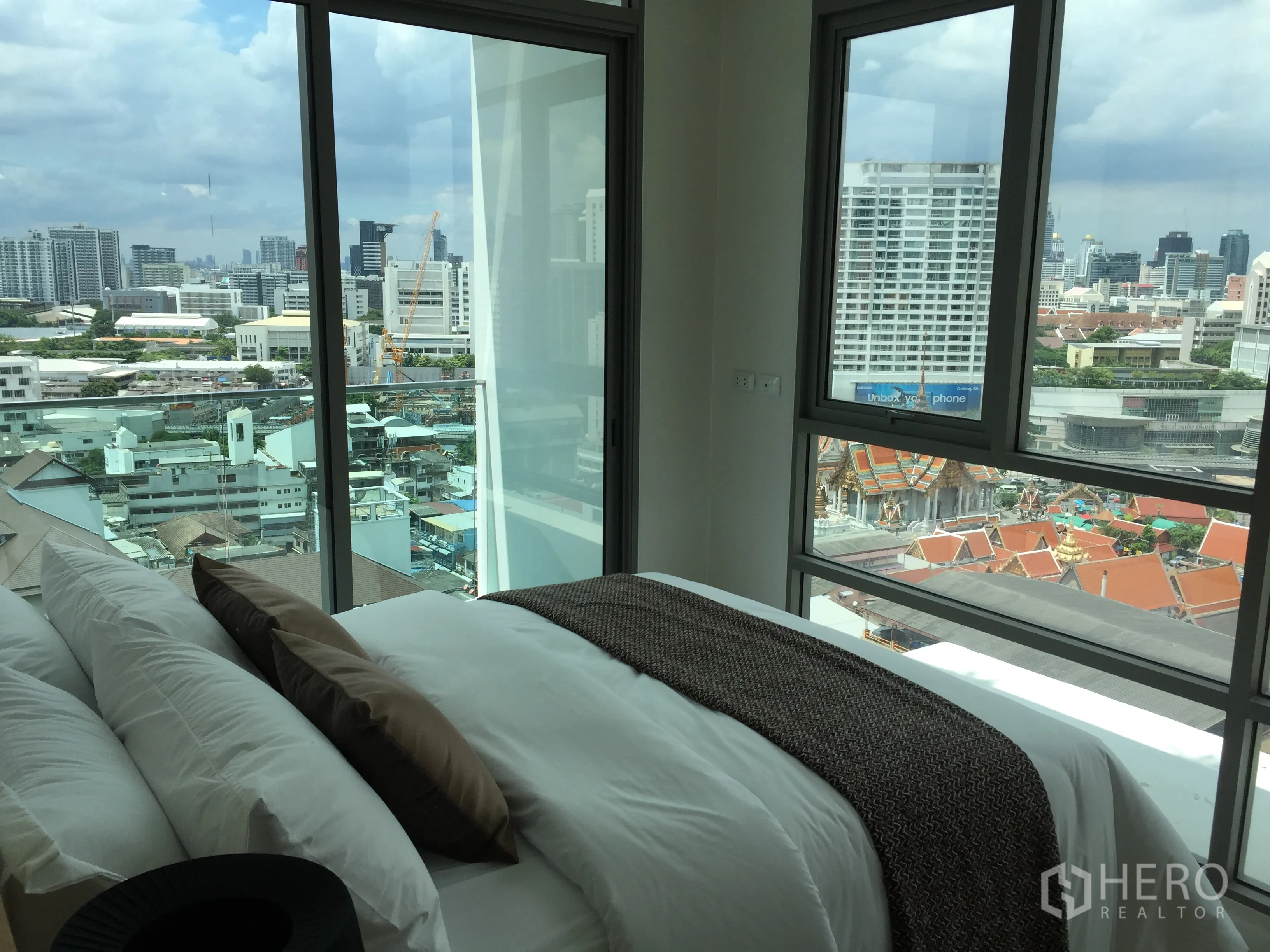 Condominium for sale in Bang Rak, Bangkok - Corner bedroom with floor-to-ceiling windows and panoramic Bangkok skyline with temple rooftops.