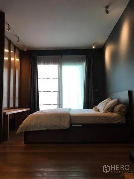 联排别墅 出售在Wang Thonglang, Bangkok - 主卧木地板，深色强调墙，大幅阳台门与内置书桌。