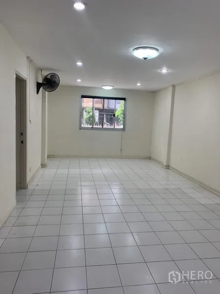 联排别墅 出租在Wang Thonglang, Bangkok - 细长客厅，白色地砖、窗户、顶灯与壁扇。