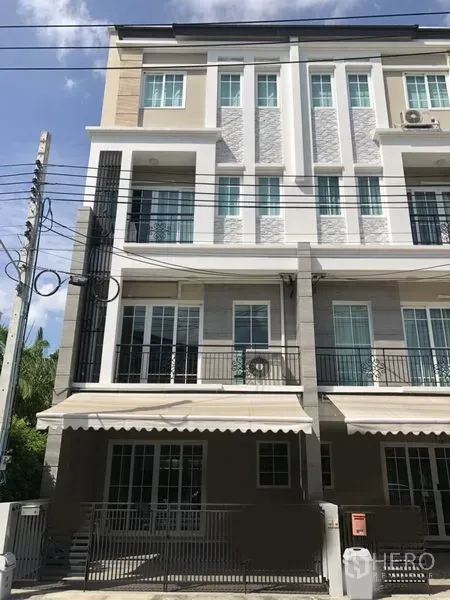联排别墅 出租在Bang Na, Bangkok - Bang Na 现代多层联排别墅外立面，带阳台、遮阳棚与前院大门。