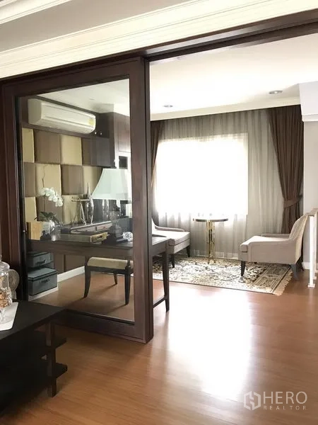 Townhouse for rent or sale in Bang Kho Laem, Bangkok - Home office with glass partition, desk, armchairs and natural light through a curtained window.