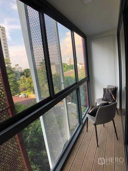公寓 出租在Watthana, Bangkok - 封闭式阳台，木地板，两把椅子，可眺望树木与周边建筑