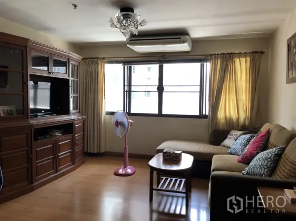 公寓 出租在Pathum Wan, Bangkok - 客厅配转角沙发、木质电视柜、木地板与大窗采光。