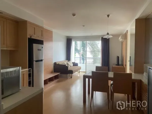 公寓 出租在Watthana, Bangkok - 从厨房望向起居区，可见餐桌、推拉玻璃门以及窗外绿景。