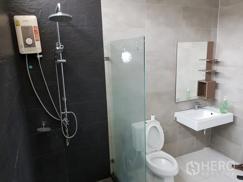 Detached House for sale in Samut Prakan - Modern bathroom with glass shower screen, rain shower, water heater, toilet and sink.