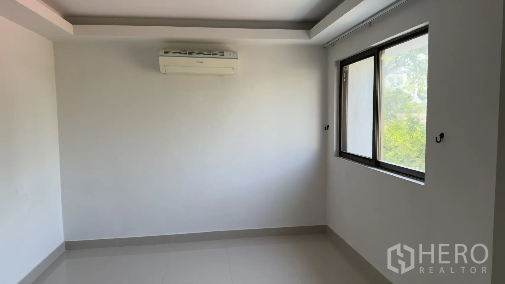 联排别墅 for rent in Watthana, Bangkok - 舒适卧室配空调与两扇窗，可见绿意。