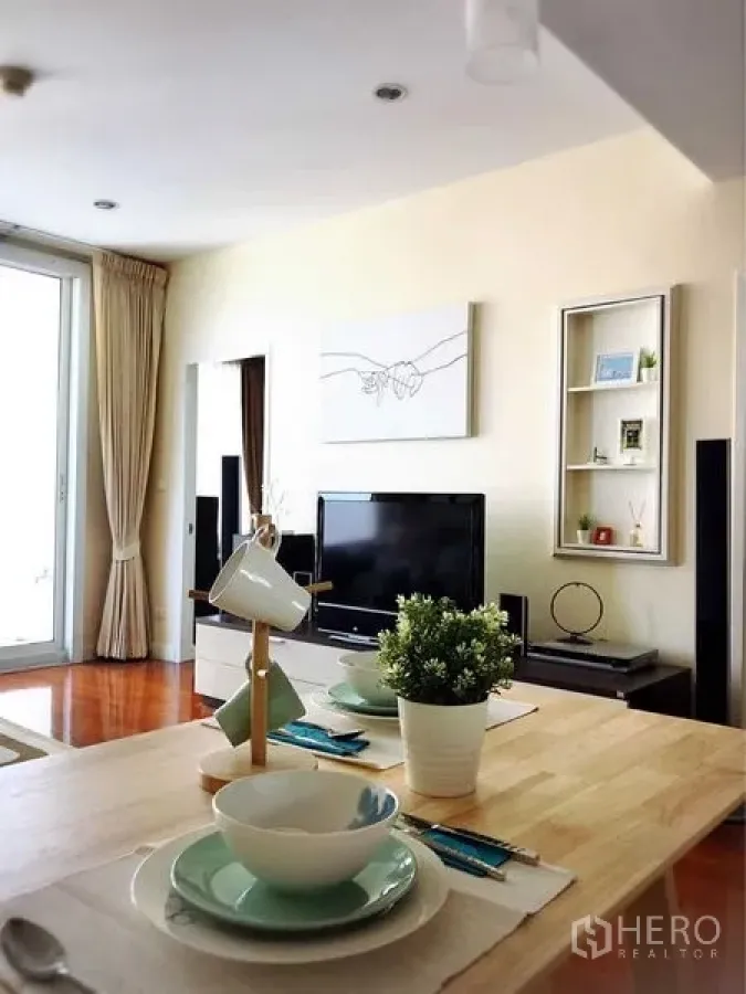 Condominium for rent in Khlong Toei, Bangkok - Open-plan living and dining area with TV unit and sliding door to balcony.