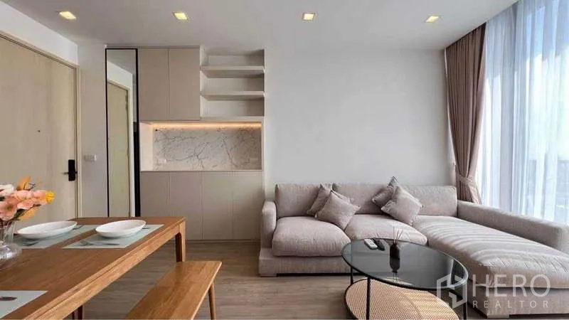 公寓 出租在Watthana, Bangkok - 温馨起居区，L 型沙发与背光大理石饰面柜体。
