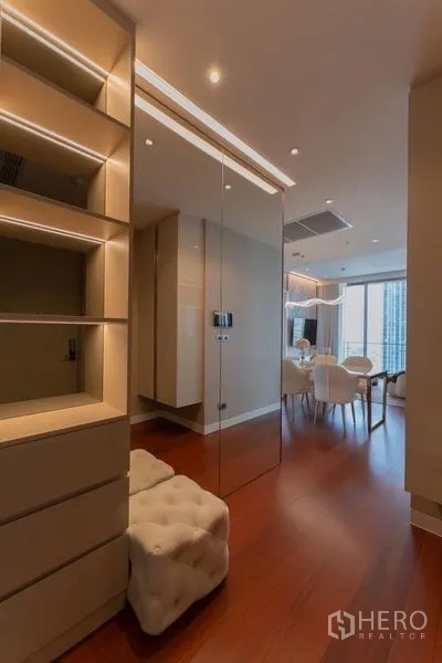 Condominium for rent in Watthana, Bangkok - Entrance corridor with mirrored wall and built‑in shelving opening to a bright dining space.