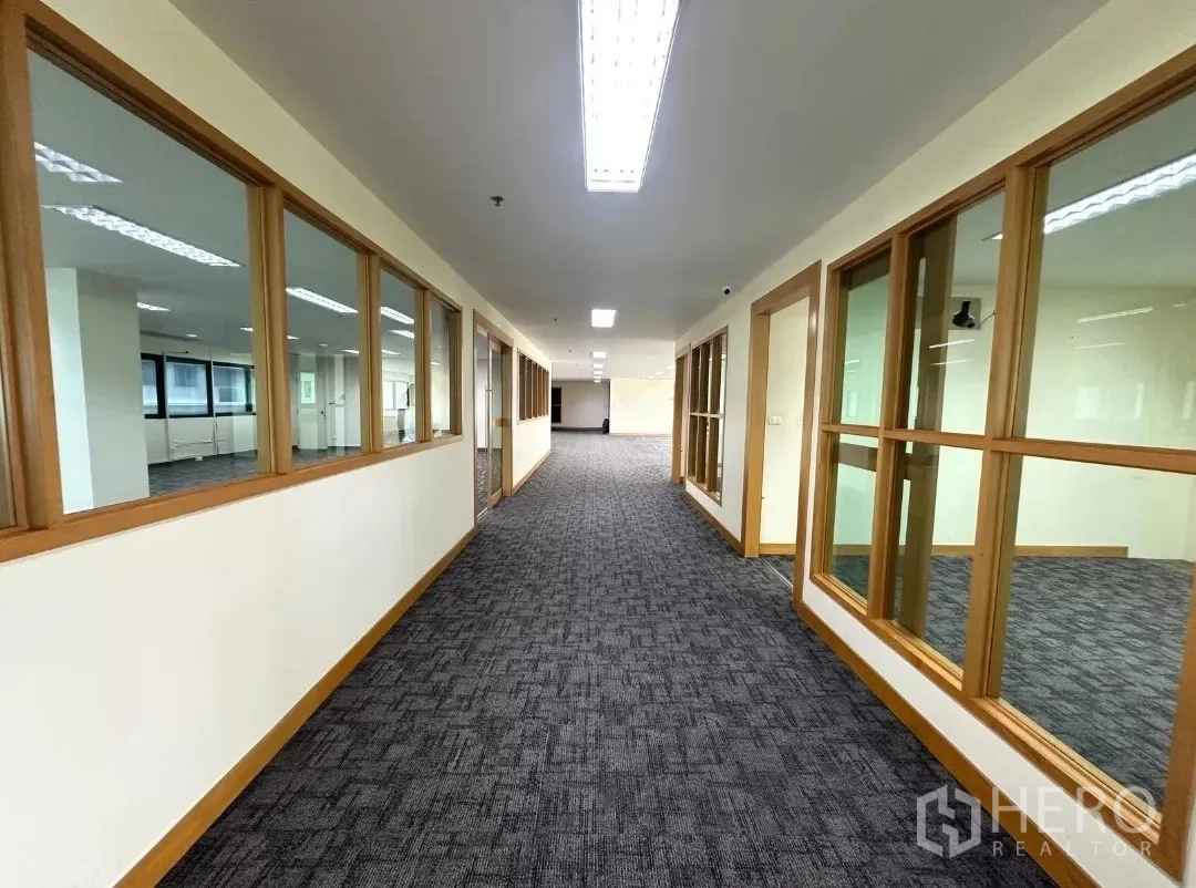 Office Space for rent in Bang Rak, Bangkok - Long corridor lined with interior glass windows leading to work area.