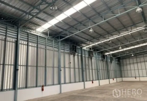 Warehouse for rent in Suan Luang, Bangkok - Warehouse side wall showing louvered vents, high-bay lights, and fire extinguishers along the perimeter.