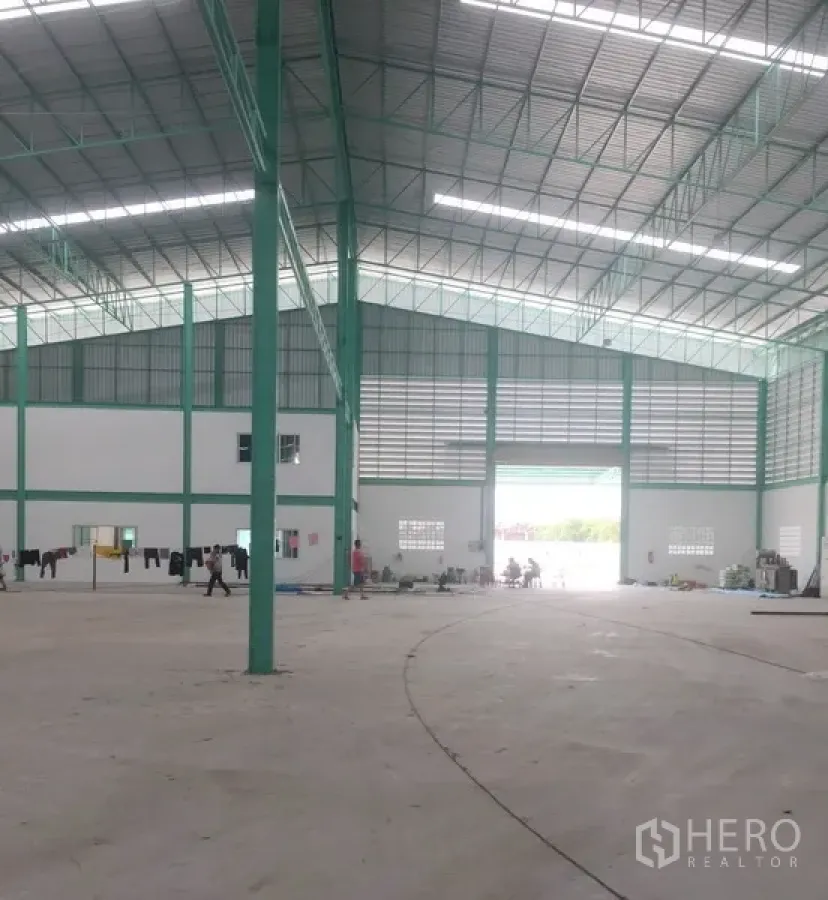 货栈 出租在Samut Prakan - 高挑层高的仓库内部，绿色钢结构、屋顶采光带与大型装卸入口。
