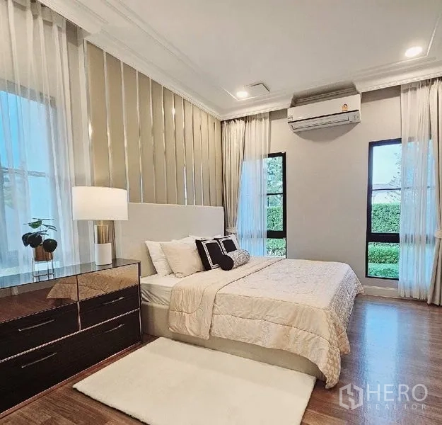 Detached House for rent or sale in Saphan Sung, Bangkok - Bright beige-themed bedroom with large windows and garden views.