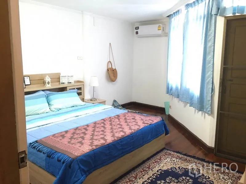 联排别墅 出租在Khlong Toei, Bangkok - 卧室带蓝色窗帘、木地板、双人床与床头灯。