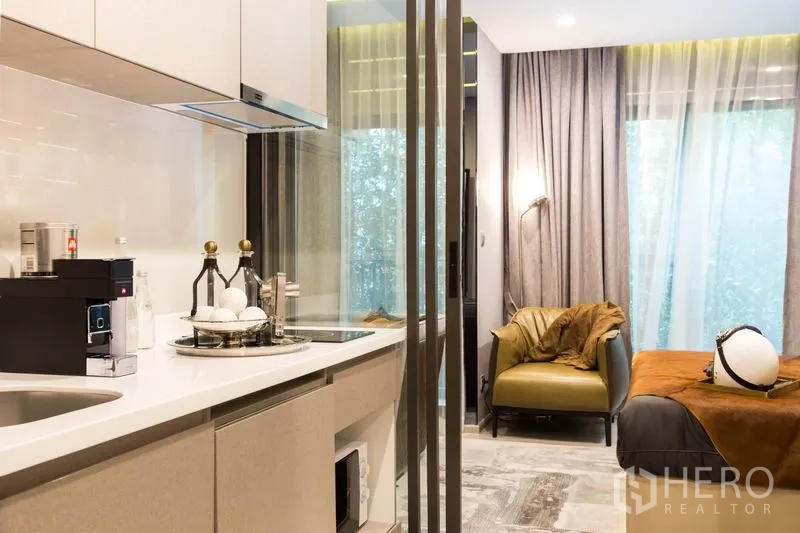 公寓 出售在Ratchathewi, Bangkok - 紧凑小厨房，白色台面与电器，旁接休闲椅与卧床。