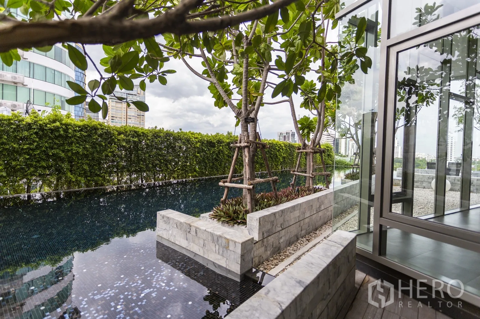 公寓 出租在Watthana, Bangkok - 屋顶景观水池，树木与绿篱相伴，旁是玻璃亭。