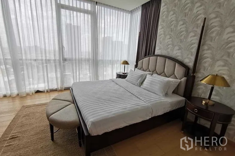 Condominium for rent or sale in Watthana, Bangkok - Corner bedroom with upholstered headboard and panoramic glazing.