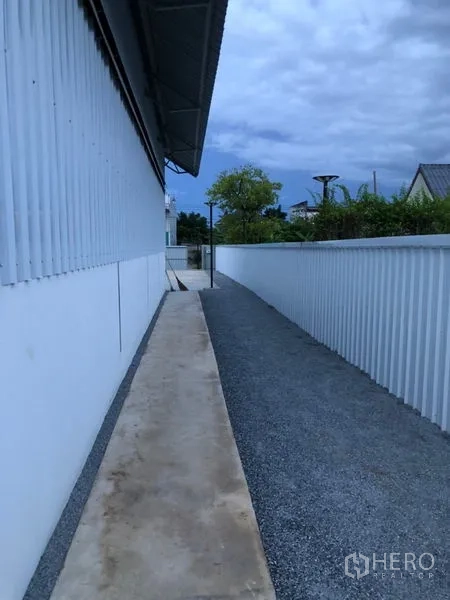 Warehouse for rent in Bueng Kum, Bangkok - Long service path with gravel strip running along the warehouse’s metal fence